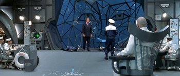 Movie still from “Austin Powers in Goldmember” (2002), directed by Jay Roach – A man in a suit standing next to another man in a uniform; Wide shot, High angle