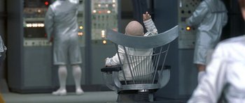 Movie still from “Austin Powers in Goldmember” (2002), directed by Jay Roach – A bald man sitting in a chair in front of a control room; Medium shot, High angle