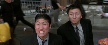 Movie still from “Austin Powers in Goldmember” (2002), directed by Jay Roach – Two asian men in suits and ties posing for a picture; Close Up shot, Low angle