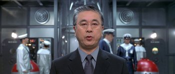 Movie still from “Austin Powers in Goldmember” (2002), directed by Jay Roach – A man in a suit and tie in front of other men; Close Up shot, Low angle