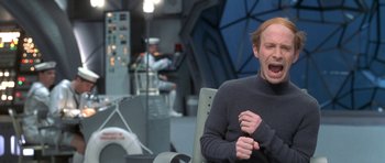 Movie still from “Austin Powers in Goldmember” (2002), directed by Jay Roach – A man in a grey sweater is yawning in an office; Medium shot, Over the shoulder angle
