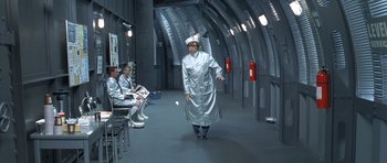 Movie still from “Austin Powers in Goldmember” (2002), directed by Jay Roach – A man in a silver lab coat stands in front of a group of people; Wide shot, Low angle