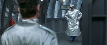 Movie still from “Austin Powers in Goldmember” (2002), directed by Jay Roach – A man in a silver coat standing next to another man; Wide shot, Over the shoulder angle