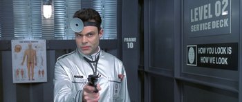 Movie still from “Austin Powers in Goldmember” (2002), directed by Jay Roach – A man in a silver jacket holding a gun; Close Up shot, Over the shoulder angle
