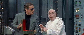 Movie still from “Austin Powers in Goldmember” (2002), directed by Jay Roach – A man in a white suit and a man in a black suit; Medium shot, Over the shoulder angle