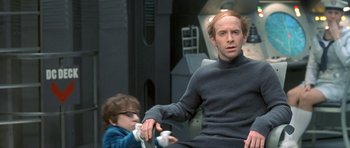 Movie still from “Austin Powers in Goldmember” (2002), directed by Jay Roach – A man sitting on a chair holding a wii controller; Medium shot, Low angle