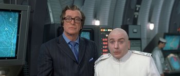 Movie still from “Austin Powers in Goldmember” (2002), directed by Jay Roach – A man and a bald man standing next to each other; Medium shot, Low angle