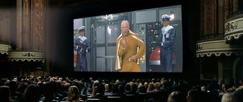 Movie still from “Austin Powers in Goldmember” (2002), directed by Jay Roach – A group of people sitting in front of a movie screen; Wide shot, Low angle