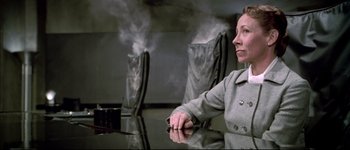 Movie still from “Austin Powers: International Man of Mystery” (1997), directed by Jay Roach – A woman sitting at a table with steam coming out of her mouth; Medium shot, Low angle