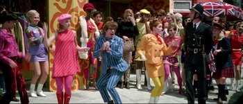 Movie still from “Austin Powers: International Man of Mystery” (1997), directed by Jay Roach – A group of people dressed up in colorful outfits; Wide shot, Low angle