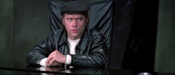 Movie still from “Austin Powers: International Man of Mystery” (1997), directed by Jay Roach – A man sitting in a chair wearing a hat; Close Up shot, Over the shoulder angle