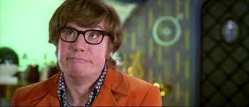 Movie still from “Austin Powers: International Man of Mystery” (1997), directed by Jay Roach – A man in an orange jacket with glasses looking up; Close Up shot, Over the shoulder angle