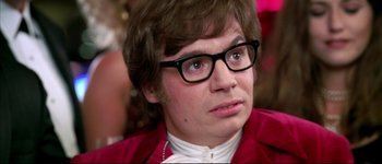 Movie still from “Austin Powers: International Man of Mystery” (1997), directed by Jay Roach – A young man wearing glasses and a red jacket looks to his left; Close Up shot, High angle