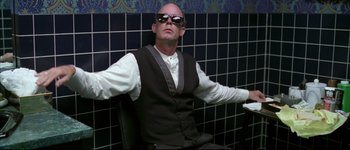 Movie still from “Austin Powers: International Man of Mystery” (1997), directed by Jay Roach – A man sitting in a chair wearing sunglasses; Medium shot, Low angle