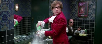 Movie still from “Austin Powers: International Man of Mystery” (1997), directed by Jay Roach – A man in a red suit is holding a bag of candy; Medium shot, Low angle