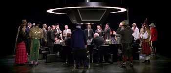 Movie still from “Austin Powers: International Man of Mystery” (1997), directed by Jay Roach – A group of men standing around a table; Wide shot, High angle