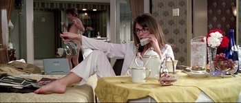 Movie still from “Austin Powers: International Man of Mystery” (1997), directed by Jay Roach – A woman sitting at a table talking on a phone; Medium shot, Over the shoulder angle