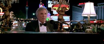 Movie still from “Austin Powers: International Man of Mystery” (1997), directed by Jay Roach – A man in a tuxedo sitting at a table; Medium shot, Low angle