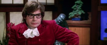 Movie still from “Austin Powers: International Man of Mystery” (1997), directed by Jay Roach – A man in a red jacket and a white bow tie; Close Up shot, Over the shoulder angle