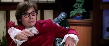 Movie still from “Austin Powers: International Man of Mystery” (1997), directed by Jay Roach – A man in a red jacket sitting in front of a statue; Close Up shot, Over the shoulder angle
