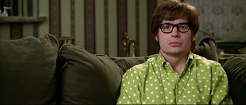 Movie still from “Austin Powers: International Man of Mystery” (1997), directed by Jay Roach – A man sitting on top of a couch wearing a polka dot shirt; Close Up shot, High angle