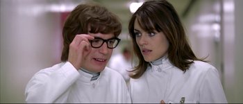 Movie still from “Austin Powers: International Man of Mystery” (1997), directed by Jay Roach – A man and a woman wearing lab coats and glasses; Close Up shot, Over the shoulder angle