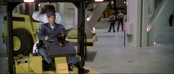 Movie still from “Austin Powers: International Man of Mystery” (1997), directed by Jay Roach – A man sitting on a forklift in an industrial setting; Wide shot, Low angle