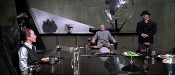 Movie still from “Austin Powers: International Man of Mystery” (1997), directed by Jay Roach – A man sitting on a chair in a room; Wide shot, High angle