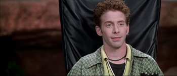 Movie still from “Austin Powers: International Man of Mystery” (1997), directed by Jay Roach – A man sitting in a chair wearing a green shirt; Close Up shot, High angle