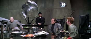 Movie still from “Austin Powers: International Man of Mystery” (1997), directed by Jay Roach – Two men sitting at a dinner table in suits; Wide shot, High angle
