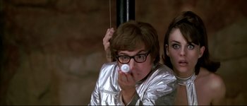 Movie still from “Austin Powers: International Man of Mystery” (1997), directed by Jay Roach – A woman holding a video game controller in front of another woman; Close Up shot, Low angle