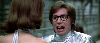 Movie still from “Austin Powers: International Man of Mystery” (1997), directed by Jay Roach – A man in a silver suit is looking at a woman in a silver suit; Close Up shot, Over the shoulder angle