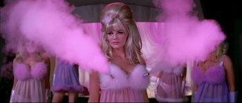 Movie still from “Austin Powers: International Man of Mystery” (1997), directed by Jay Roach – A woman in a pink dress and a white hat; Medium shot, Low angle