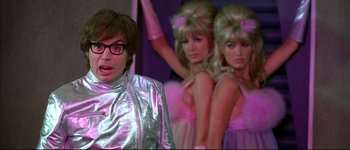 Movie still from “Austin Powers: International Man of Mystery” (1997), directed by Jay Roach – A man in a silver suit and three women in pink dresses; Medium shot, Low angle