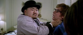 Movie still from “Austin Powers: International Man of Mystery” (1997), directed by Jay Roach – A man in a hat and a man in a suit and a tie; Close Up shot, Over the shoulder angle