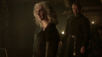 Movie still from “Game of Thrones” (2011), created by D.B. Weiss – A man standing next to another man in a dark room; Medium shot, Over the shoulder angle