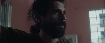 Movie still from “Stars at Noon” (2022), directed by Claire Denis – A person with long hair and a beard; Close Up shot, Low angle