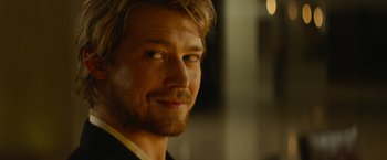 Movie still from “Stars at Noon” (2022), directed by Claire Denis – A person wearing a suit and tie; Close Up shot, Over the shoulder angle