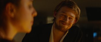 Movie still from “Stars at Noon” (2022), directed by Claire Denis – A person wearing a suit and tie; Close Up shot, Over the shoulder angle