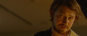 Movie still from “Stars at Noon” (2022), directed by Claire Denis – A person wearing a black shirt; Close Up shot, Over the shoulder angle