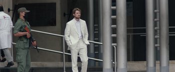 Movie still from “Stars at Noon” (2022), directed by Claire Denis – A man in a white suit standing next to a railing; Wide shot, Low angle
