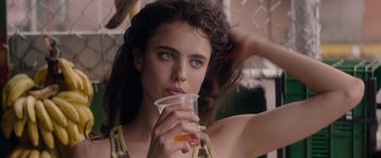 Movie still from “Stars at Noon” (2022), directed by Claire Denis – A young woman holding a cup of orange juice; Close Up shot, Over the shoulder angle
