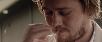 Movie still from “Stars at Noon” (2022), directed by Claire Denis – A person with a cigarette in his mouth; Extreme Close Up shot, Over the shoulder angle