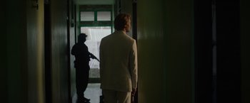 Movie still from “Stars at Noon” (2022), directed by Claire Denis – A man in a white suit is standing in a hallway; Medium shot, Over the shoulder angle