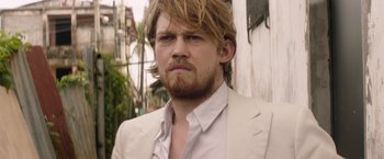 Movie still from “Stars at Noon” (2022), directed by Claire Denis – A person wearing a suit and beard; Close Up shot, Over the shoulder angle