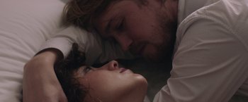 Movie still from “Stars at Noon” (2022), directed by Claire Denis – A man and a woman laying in a bed together; Close Up shot, Overhead angle