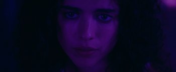 Movie still from “Stars at Noon” (2022), directed by Claire Denis – A woman's face in a purple light; Close Up shot, Low angle