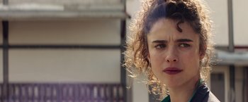 Movie still from “Stars at Noon” (2022), directed by Claire Denis – A person with curly hair; Close Up shot, Over the shoulder angle