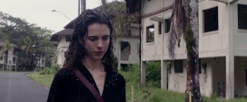 Movie still from “Stars at Noon” (2022), directed by Claire Denis – A woman in black shirt standing in front of a building; Close Up shot, Over the shoulder angle
