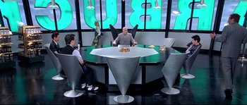 Movie still from “Austin Powers: The Spy Who Shagged Me” (1999), directed by Jay Roach – Two men sitting at a table in front of a woman; Wide shot, High angle